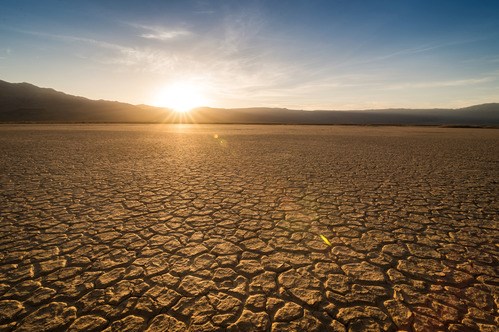 Sunbaked, cracked earth stretches from foreground and covers 2/3 of the image.