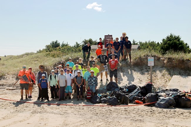 Volunteer beach cleanup crew with their full bags of trash on the beach