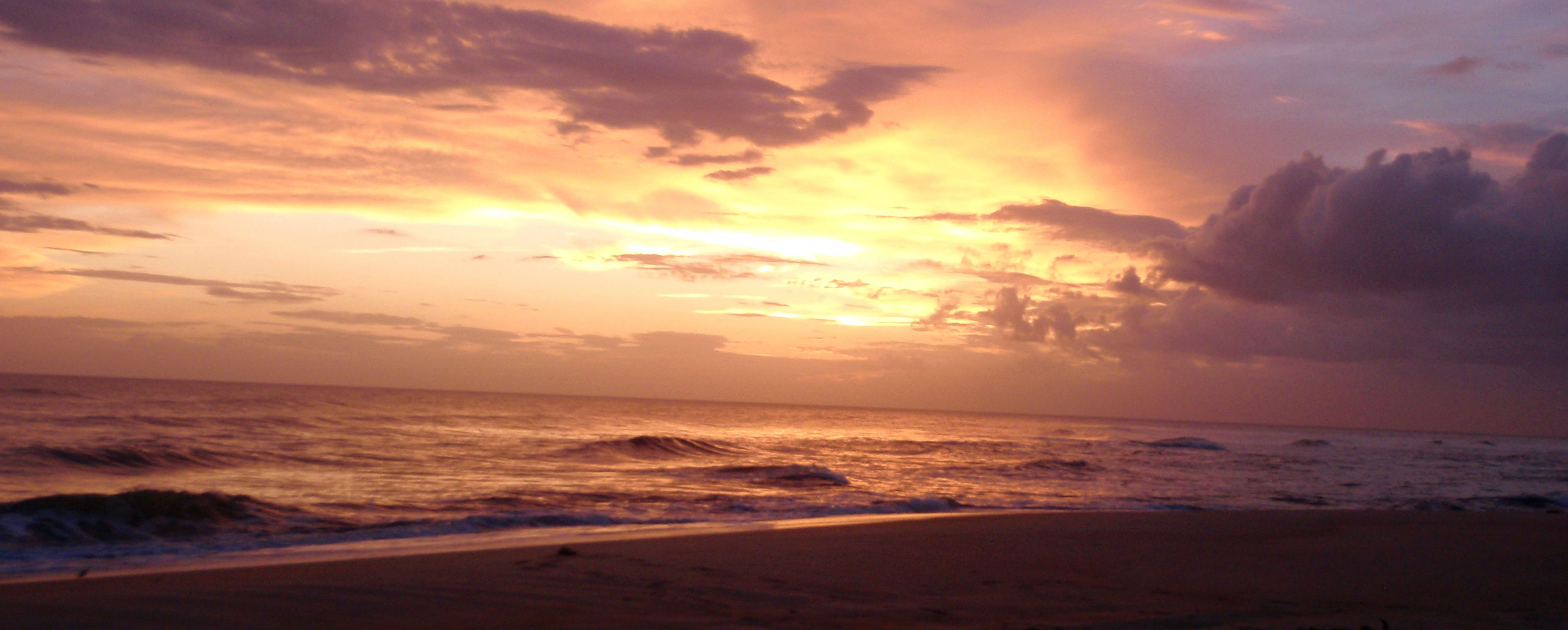 The orange glow of the last rays of sunlight paint the sky and waters along the beach in Cape Lookout.