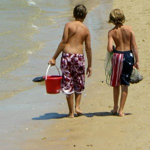 Two boys walk on the beach.