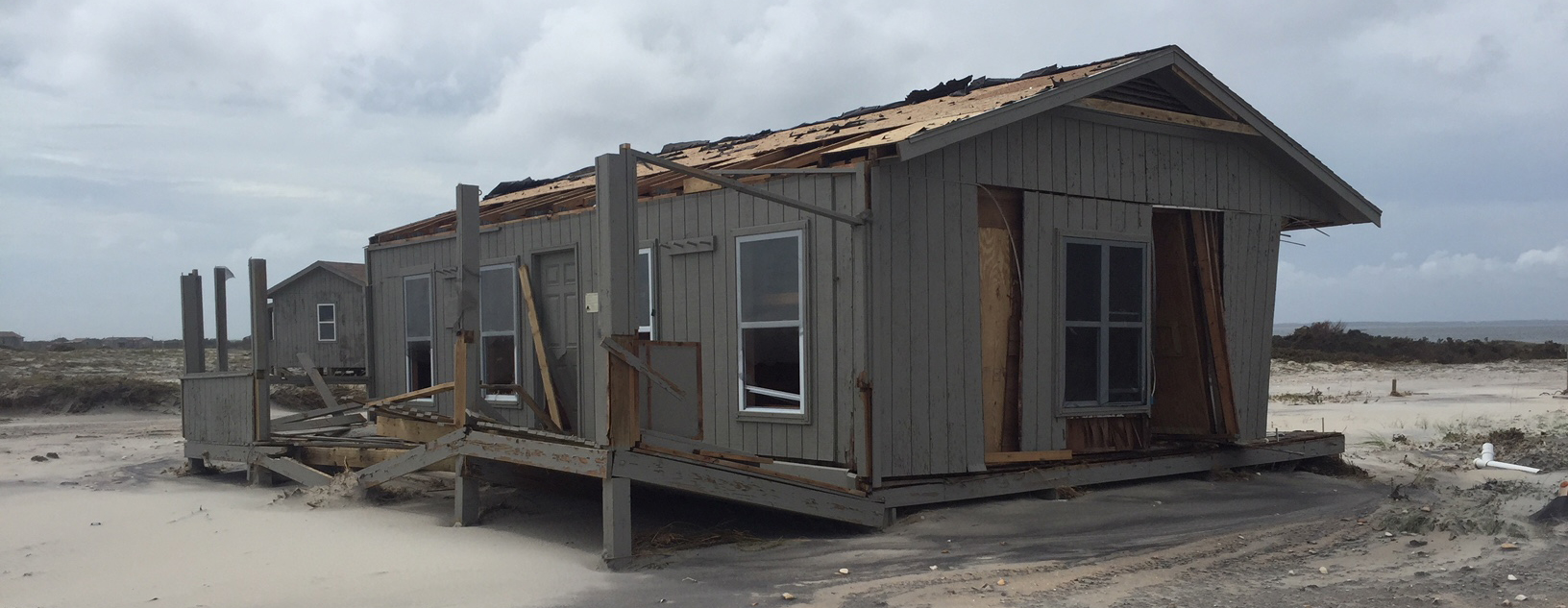 Cape Lookout Cabin A one story cabin on a beach sits severely damaged after a hurricane.