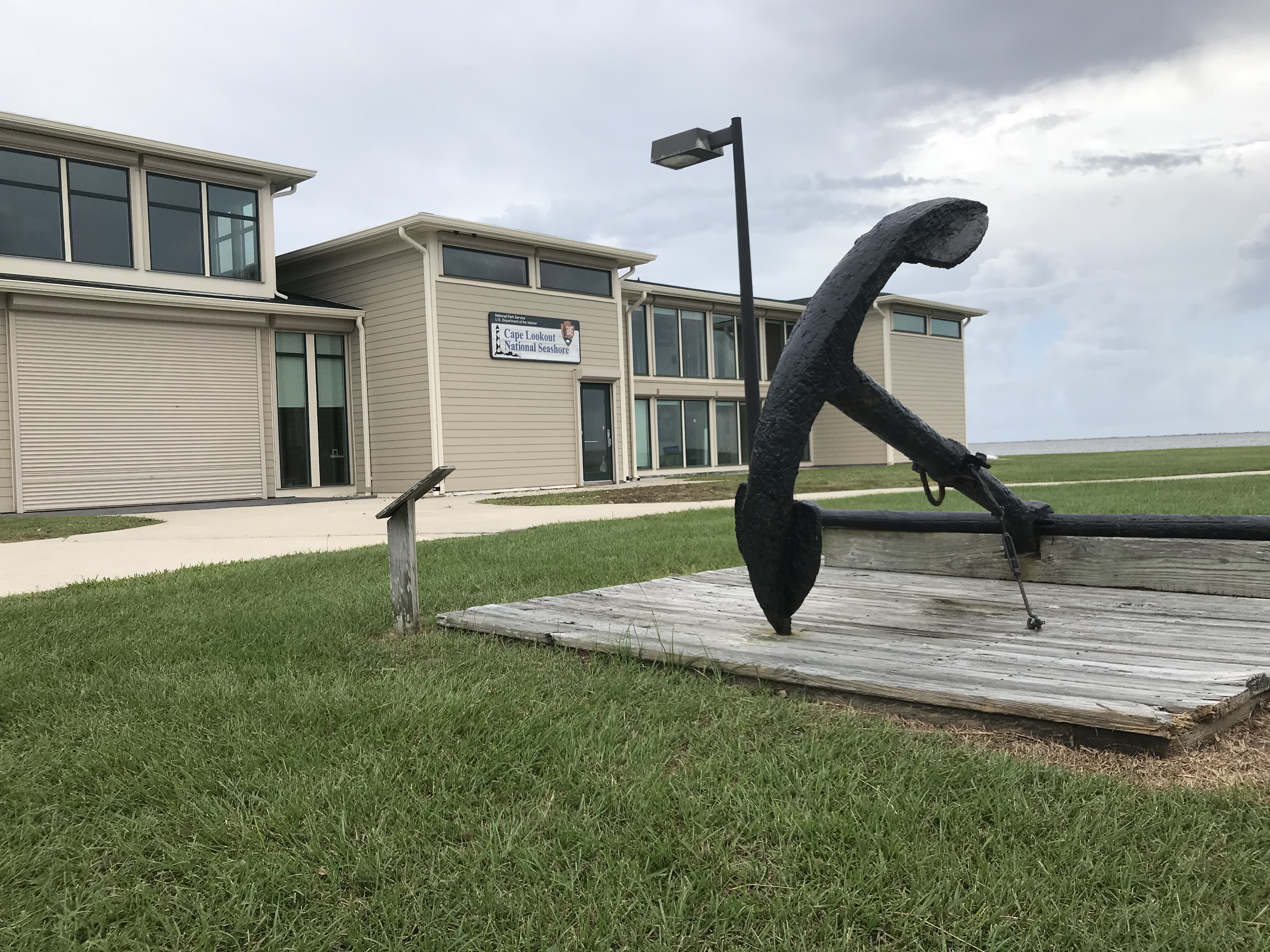 A large boat anchor sits on a wood platform in front of the Harkers Island Visitor Center in Cape Lookout National Seashore.