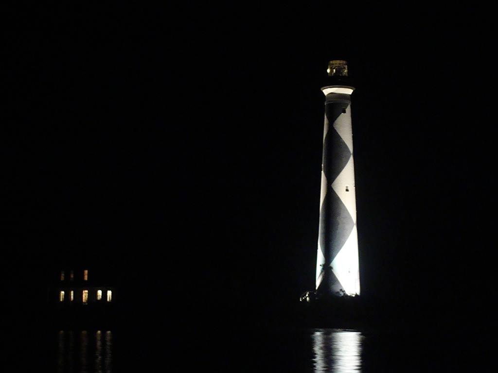 Cape Lookout Lighthouse tower and Keepers Quarters at night night illumination of the exterior of the lighthouse tower and the Keepers Quarters windows lit from the inside