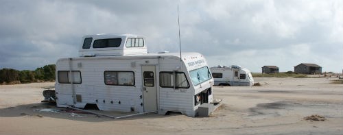 An RV buried to its wheels in sand after a hurricane. An RV buried to its wheels in sand after a hurricane.