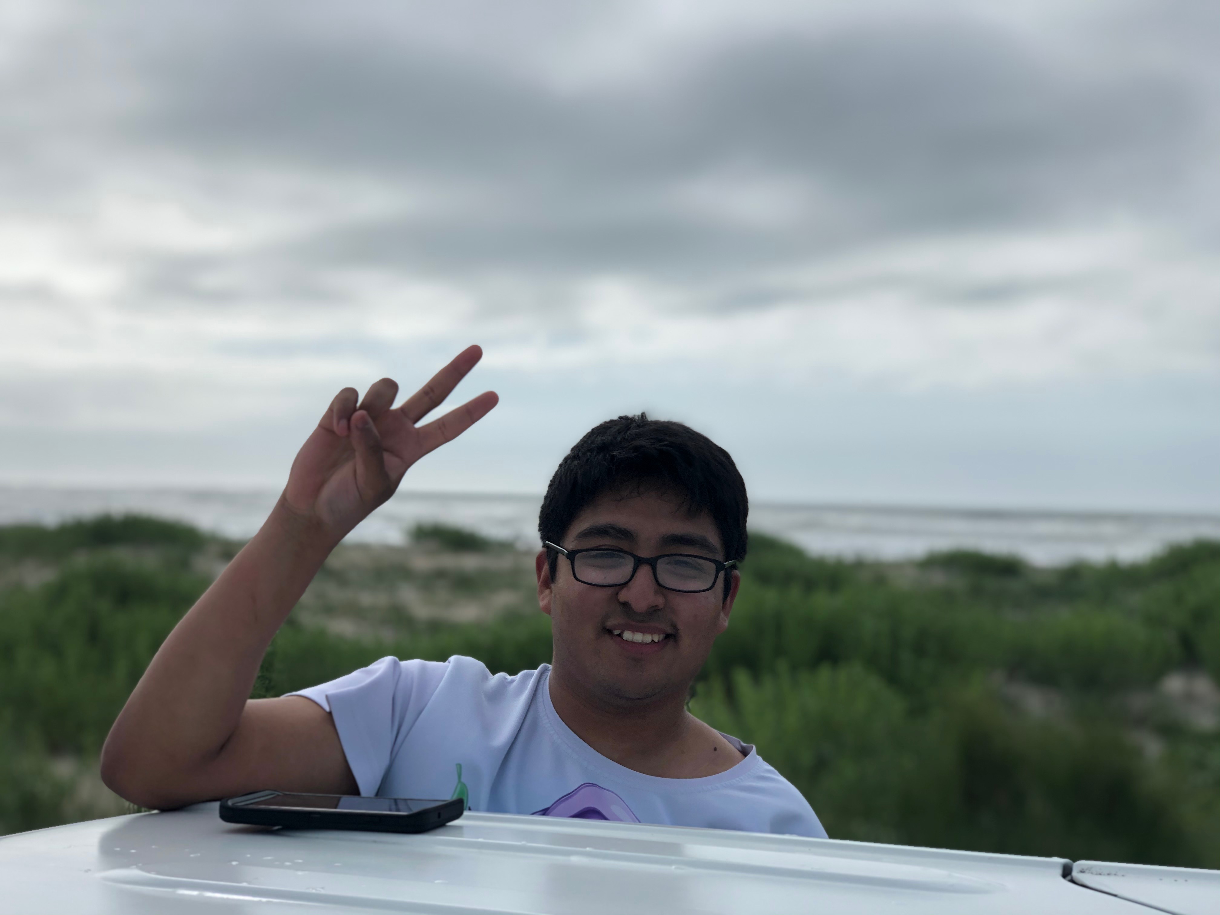 Young man wearing black glasses and flashing a V sign