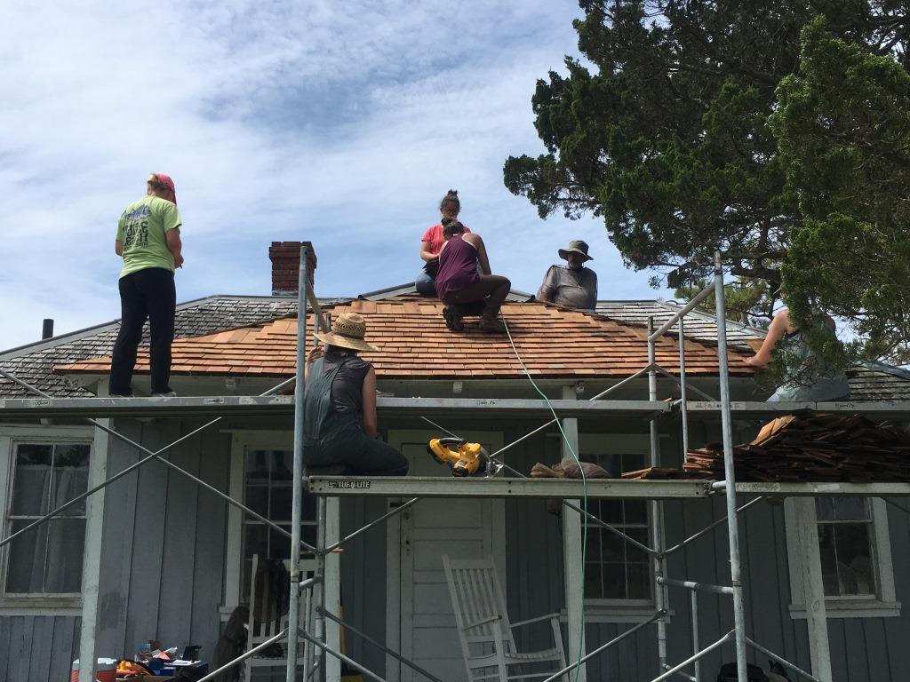 Six people work on the roof of an historic house