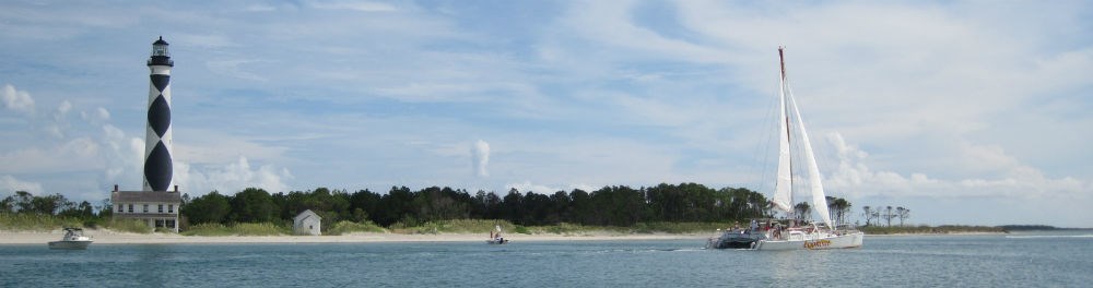 A sailboat in front of the Cape Lookout Lighthouse.