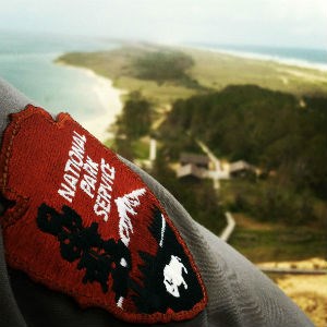 The National Patch Service patch on a ranger's shirtsleeve with the view from the top of the lighthouse in the background. The National Patch Service patch on a ranger's shirtsleeve with the view from the top of the lighthouse in the background.