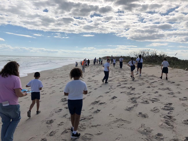 Students walk along the beach.