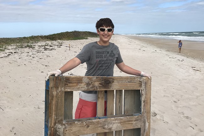 Student with wooden pallet found on the beach.