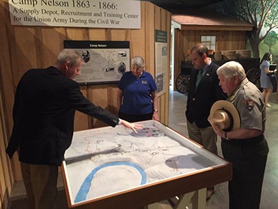 Ranger looks at relief map in museum with visitors.