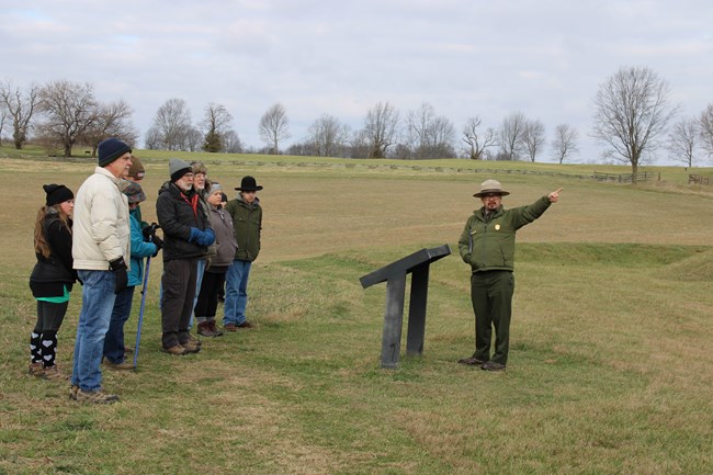 A Park Ranger delivering a program to a group of a visitors in an open field..