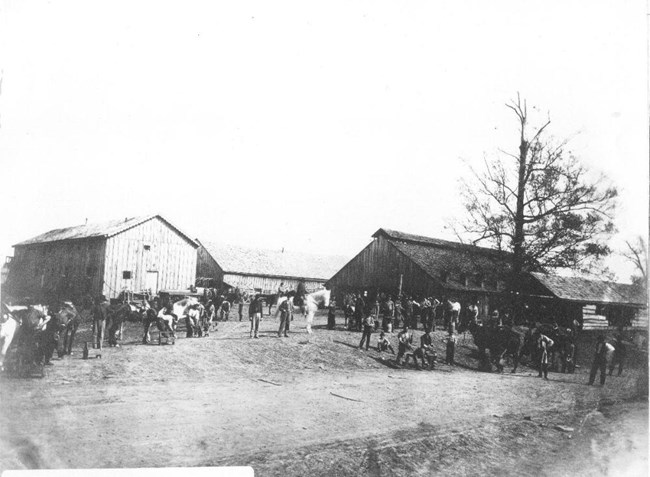 Several buildings with many men and horses standing in front during the Civil War.