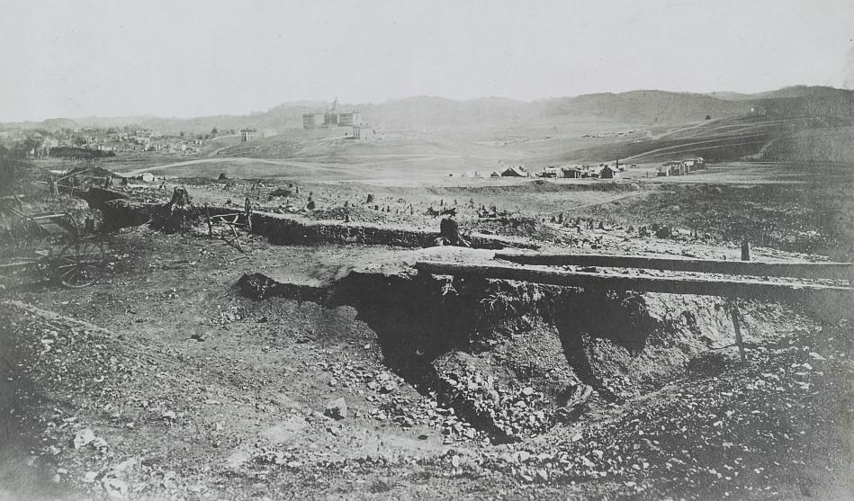 View of buildings and hill in the background during the Civil War. In the foreground are tents and earthworks.