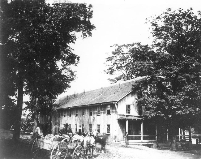 Large two-story building with horse-drawn wagon carrying several men in front during the Civil War.