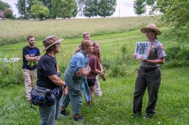 A park ranger talking to a group of people in a field.