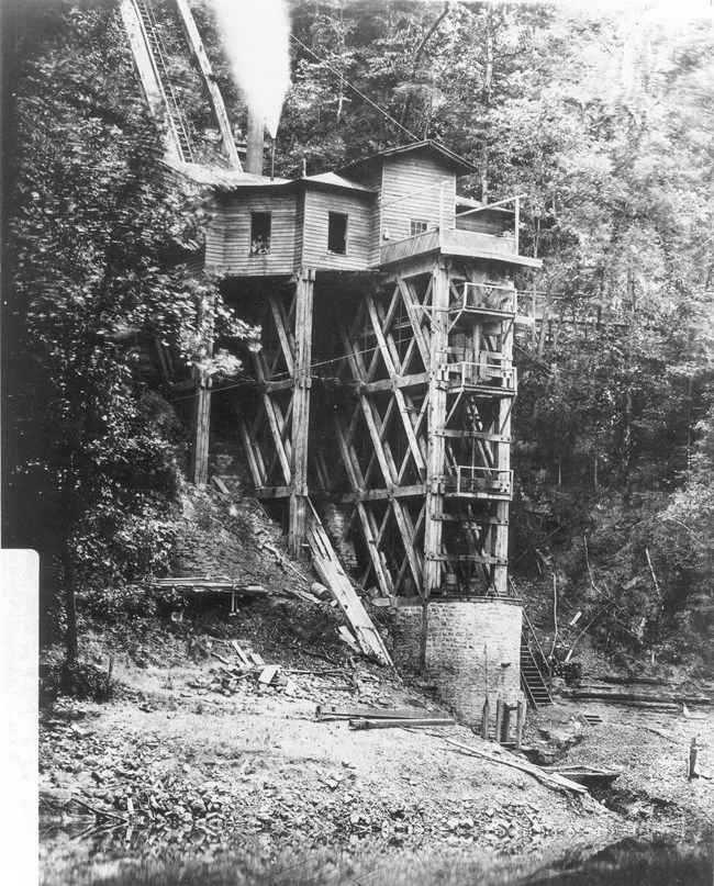 A tall wooden structure that is built on stone abutments near a water source during the Civil War. Trees surround the structure.