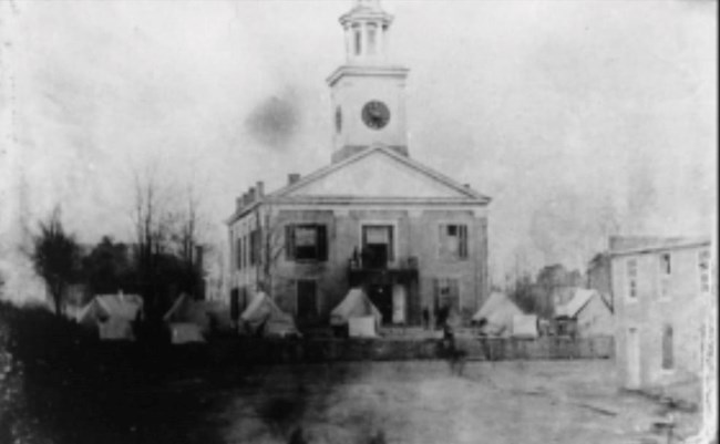 Courthouse building with tents in front during the Civil War.