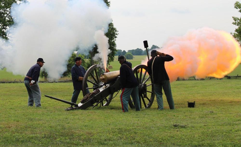 12th USCHA firing with fireball Men in Civil War uniforms fire a cannon amid a cloud of smoke and fire