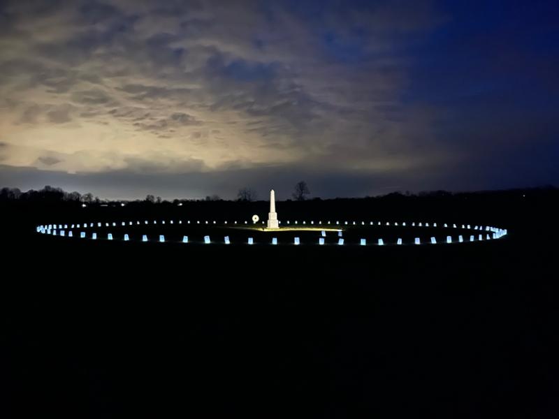 378191633_614210954218114_1405362928144144571_n A stone obelisk in a field surrounded by luminary bags.
