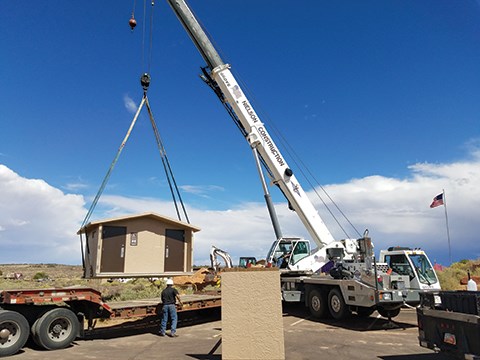 a crane lifts a tan-colored building