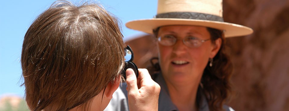 a student looks at a ranger through a magnifying lens a student looks at a ranger through a magnifying lens