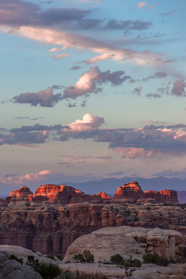 Purple and blue clouds above sandstone formations at sunset.