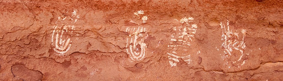 A rock surface with white, hand-shaped paintings on it