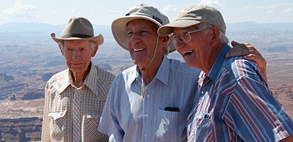 three men stand at the rim of a canyon