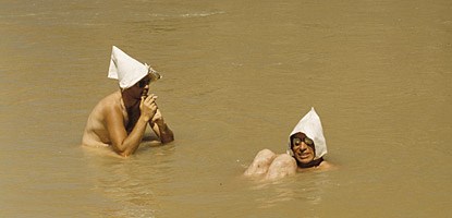 two men sit in a river