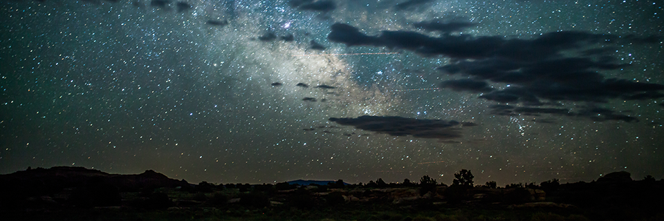 clouds stream across a star-filled sky