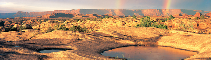 Natural stone basins with water, with rainbows in the distance Natural stone basins with water, with rainbows in the distance