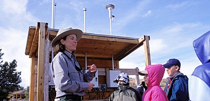 A ranger talks to kids in front of a monitoring station