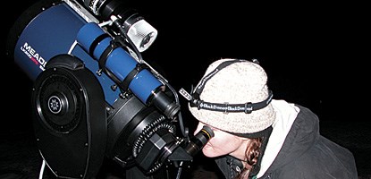 a woman looks through a telescope