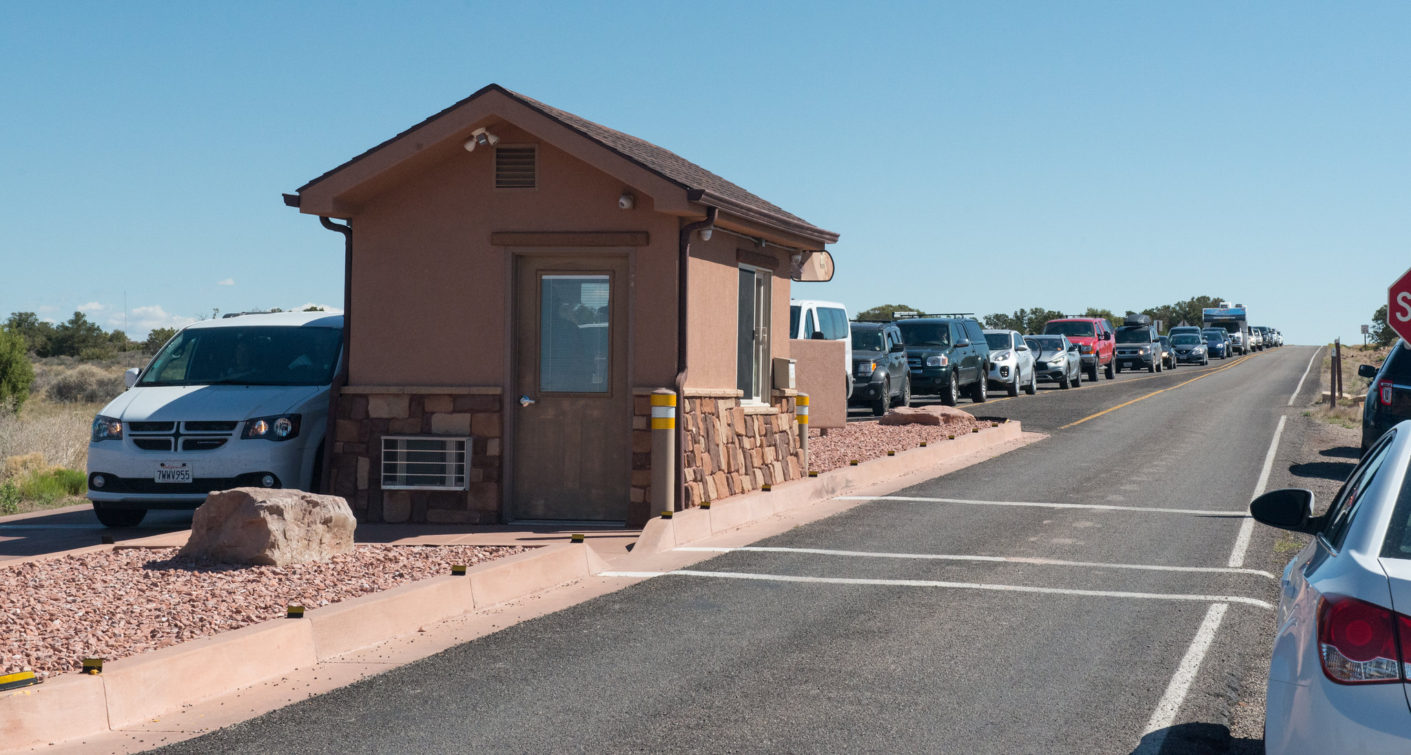 A long line of vehicles in all shapes, sizes, and colors stretches behind the Canyonlands Island in the Sky entrance station. A long line of vehicles in all shapes, sizes, and colors stretches behind the Canyonlands Island in the Sky entrance station.