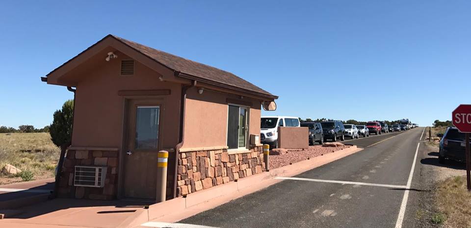 line of cars approach a small building