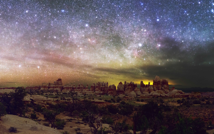 A vibrant, starry sky above rock pinnacles