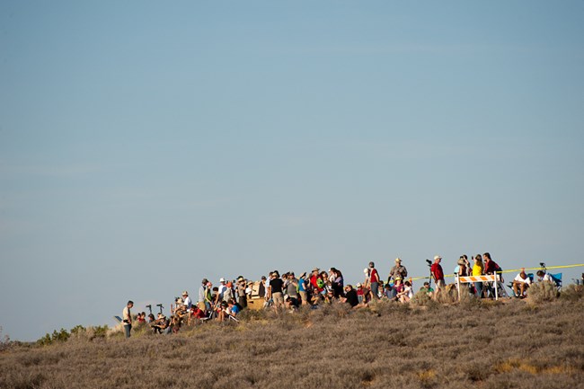A large crowd of people gather to watch the eclipse.