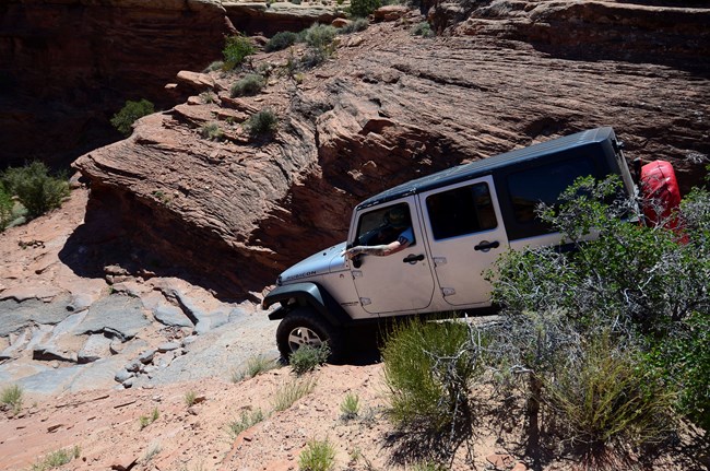 White Jeep driving down a steep technical road