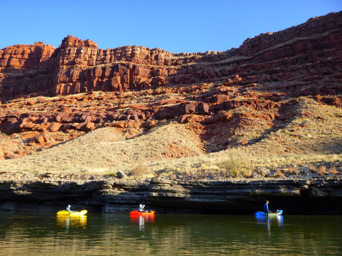 Three boats floating down a river between canyons