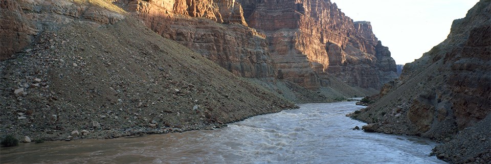 The Colorado River flows in a canyon with high cliffs. The Colorado River flows in a canyon with high cliffs.
