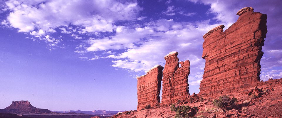 Tall thin fins of red rock with white bands on top.