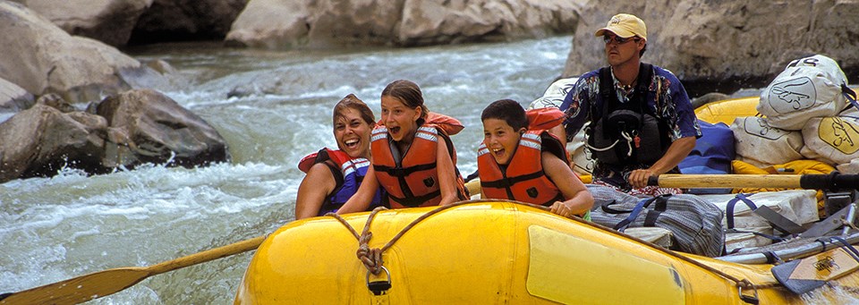 a family rides on river rapids in a yellow raft