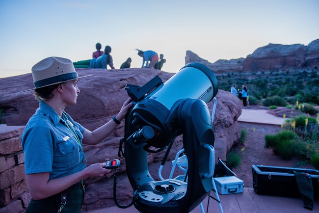 A Ranger prepares a telescope at dusk for night sky viewing.