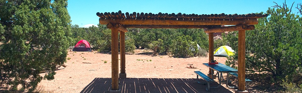 two tents and a shade structure at a campsite