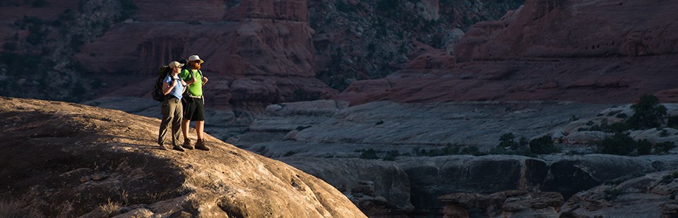 two backpackers stand on a high overlook