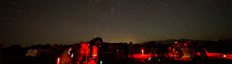 telescopes illuminated red beneath a starry sky