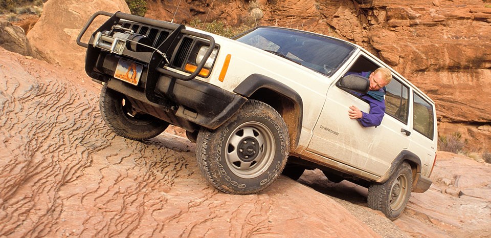 a white jeep drives up a steep rock slope