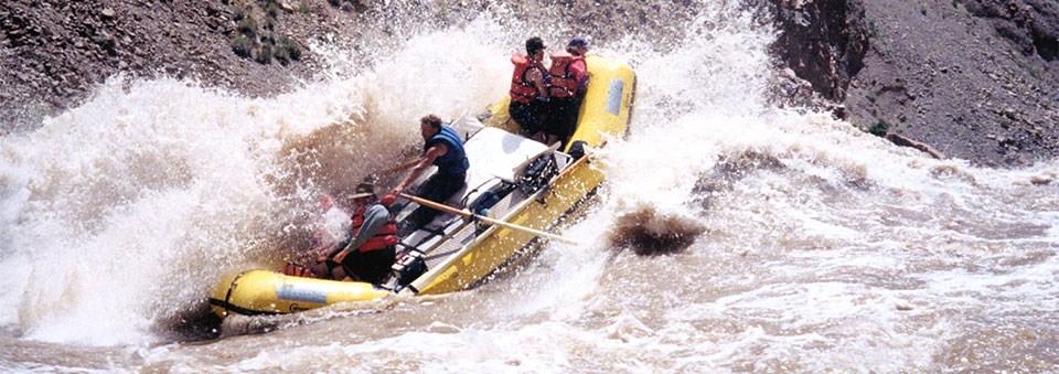 a yellow raft passes through a whitewater section on a river