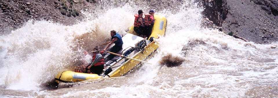 a yellow raft passes through a whitewater section on a river a yellow raft passes through a whitewater section on a river